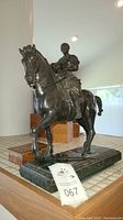Full front view of metal equestrian statue on green marble base