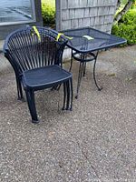 Overall view of black metal table and four chairs on concrete patio
