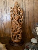 Close-up of carved wooden Krishna statue on wooden base