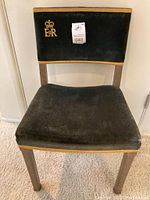 Full front view of chair showing overall form, upholstery, trim, insignia, and seat number plaque