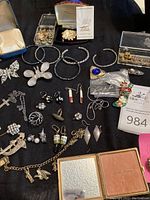 Overview of all jewelry pieces on black cloth including boxes and compact