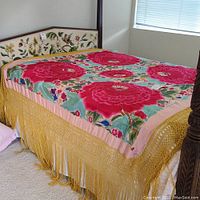 Full view of coverlet draped over bed showing overall appearance and gold fringe