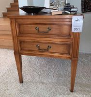 Front-facing view of side table showing rectangular top, two drawers with brass bail handles, tapered legs.