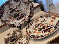 Overview of two large platters on display stand and table with smaller plates and covered dish in front