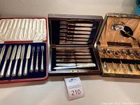 All three boxed sets displayed side by side: silver-tone forks & knives, mother-of-pearl set, and spoon set