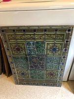 Full front view of the stained glass panel leaning against a white appliance.