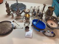 Overview of all silver and silver-plated serveware items arranged on table