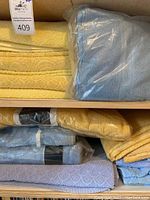 Top shelf with yellow towels and blue towel in original plastic packaging