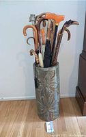 Front view of vase containing canes and umbrellas on wood floor