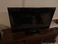 Sony TV set on a wooden cabinet with visible black stand, showing front and partial side view.