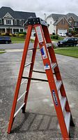 Full side view of the 6-foot orange fiberglass step ladder showing the six steps, black plastic top, and Werner brand logo on the side rail.