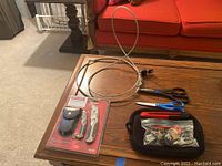 Tabletop showing all items - scissors, cable lock, box cutter, Craftsman multi-tool kit, and black zippered case with padlocks and keys