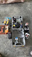 Overview of the tool lot including drill case with tools and chargers on concrete floor.