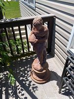 Full view of the outdoor mother statue on a deck beside a house.