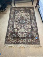 Full view of the rectangular oriental rug laid out on light-colored carpet, showing overall pattern and fringed edges.