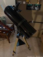 Full view of black optical tube mounted on gold tripod