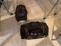 Two bags on carpet floor, one duffel and one rolling suitcase.