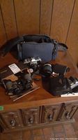 Full lot showing Canon camera with lens, flash, camera bag, and additional items on wooden furniture