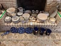 Wide view of International Stoneware dishes including plates, bowls, cups, saucers, pitcher, strainer and Pier 1 plates.