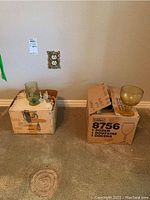 Photo of green tinted glass goblet on box with another box nearby.