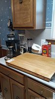 Photo of kitchen countertop showing Black and Decker coffee maker, Oster blender, cutting board, and Ritz cracker tin with small box and yellow ball on top