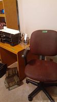 Office chair, desk organizers stacked on wooden surface, box on floor