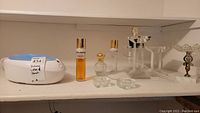 Lot displayed on a shelf with various perfume bottles, glass dishes, and decorative stands.