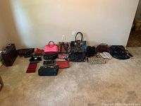 Full view of assorted handbags, purses, wallets, and a briefcase arranged on floor showing variety of shapes and colors.