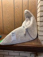 Front view of the white textured sculpture showing the mother seated with long hair holding a small child, patterns on clothing visible.