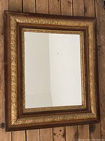 Frontal image of the antique rectangular mirror showing the gilt wooden frame with floral motifs.