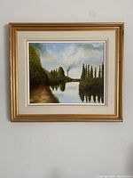 Full view of the framed oil on canvas painting showing a river landscape with trees and a factory emitting smoke in the distance.