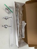Full view of the towel bar, mounting brackets, hardware, instruction manual, and packaging box showing contents.
