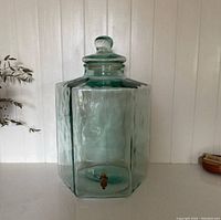 Full front view of the large hexagonal glass beverage dispenser with lid and brass spigot, highlighting size and shape.