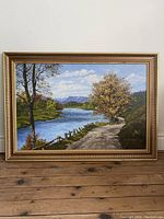 Full frontal view of framed landscape painting leaning against wall
