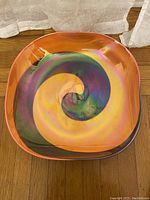 Top view of colorful Murano glass bowl with spiral design in orange, purple, green, and yellow.