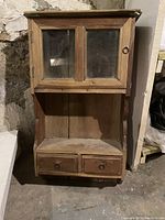 Front view of the full wooden cabinet showing glass doors, open shelf, and two bottom drawers with metal ring pulls.