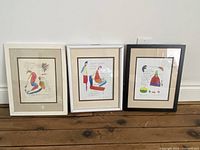 Full set of three framed Brian Andreas prints arranged side by side against a wall on wooden floor