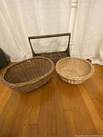 Three baskets and a rustic wooden caddy with handle displayed on wooden floor against white curtain.