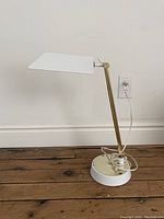 Front side view of the vintage adjustable desk lamp showing white enamel rectangular shade, brass adjustable arm, and round white enamel base with power cord.