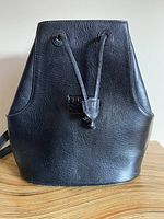 Front view showing the embossed Sergio Rossi logo and drawstring closure on stiff black leather backpack.