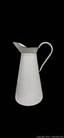 Full side view of the white enamel pitcher showing tapered body and handle.