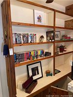 Office wooden shelves with art prints, approx 20 VHS tapes, 6 DVDs, three puzzles, coasters, and various small items.