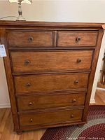 Front view of the wood 5-drawer dresser showing two smaller top drawers and three larger bottom drawers with round wooden knobs.