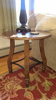 Side and top view of one wooden round end table with curved legs and metal cross brace, part of matching pair.