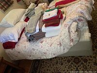 Full bed with mattress, comforter, and piled linens/towels on top, showing condition and included comforter