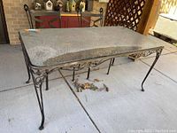 Full view of the rectangular outdoor dining table and two chairs set on concrete patio.
