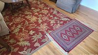 Large wool area rug from Pottery Barn in red with beige floral pattern under furniture on hardwood floor