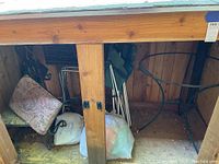 Storage shed interior showing two metal stools with patterned cushions, metal folding chairs, and bags on the floor