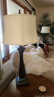 Pair of matching table lamps on a couch armrest and side table, beige couch with sheepskin throws in the background.