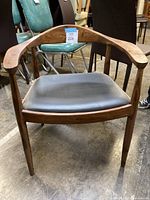 Front view of wood frame chair with black leather seat cushion.